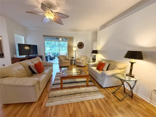 Living room with Laminate flooring, crown molding, sliding glass doors onto the Covered and screened in lanai with Golf course view, open floor plan