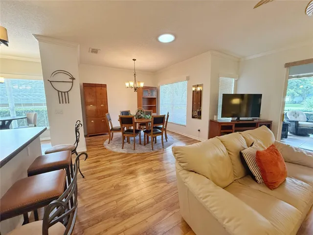View from Living room of Dining room, Kitchen and Dinette with screened and covered lanai in background with golf view, ceiling rub light for more natural lighting