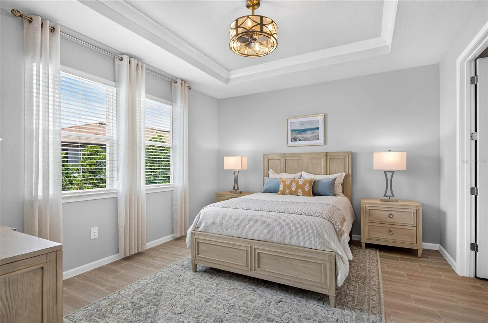 Primary suite with crown molding in trey ceiling and an elegant fandelier
