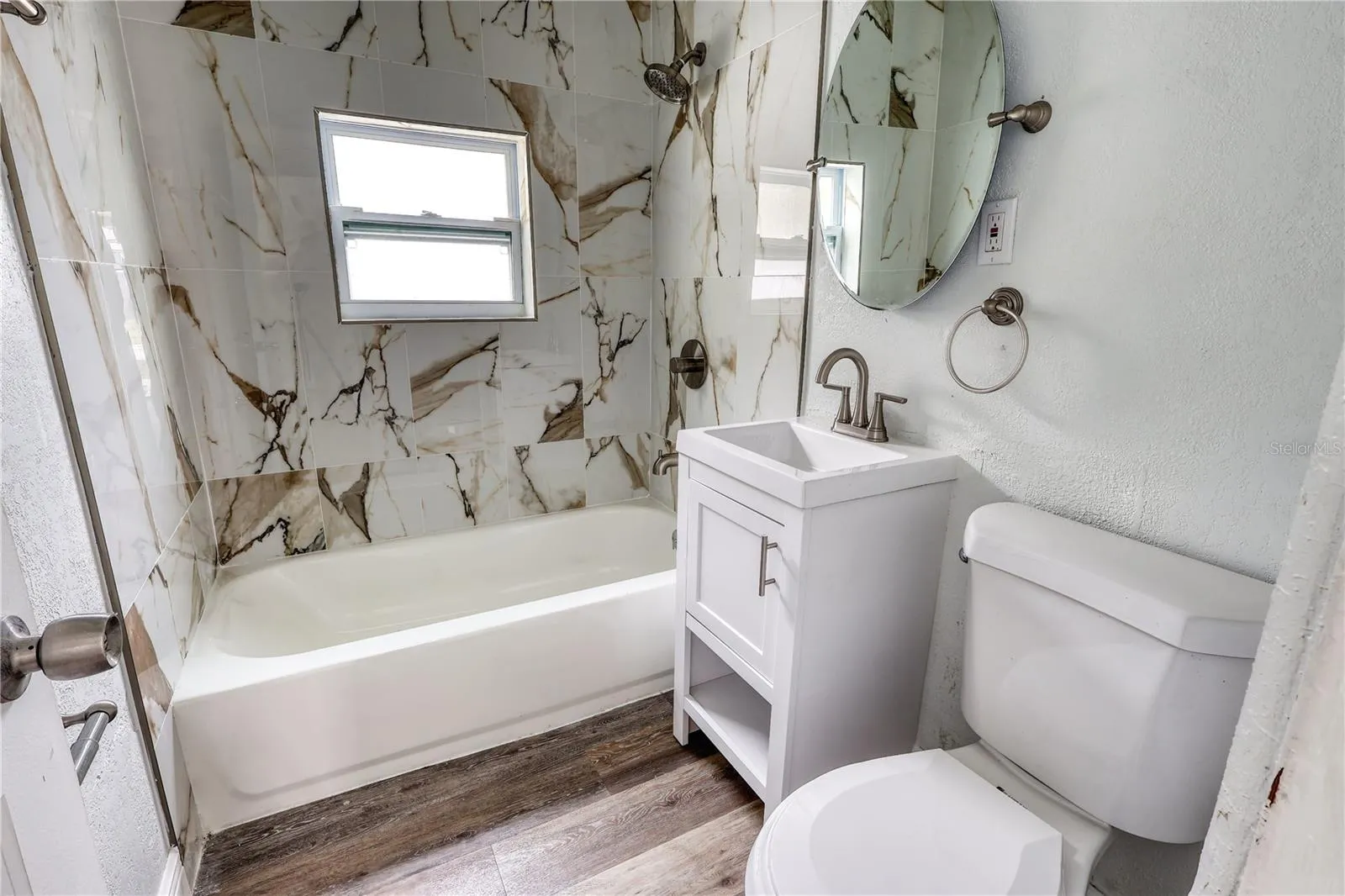 Updated bathroom featuring fully tiled walls surrounding the tub and shower.