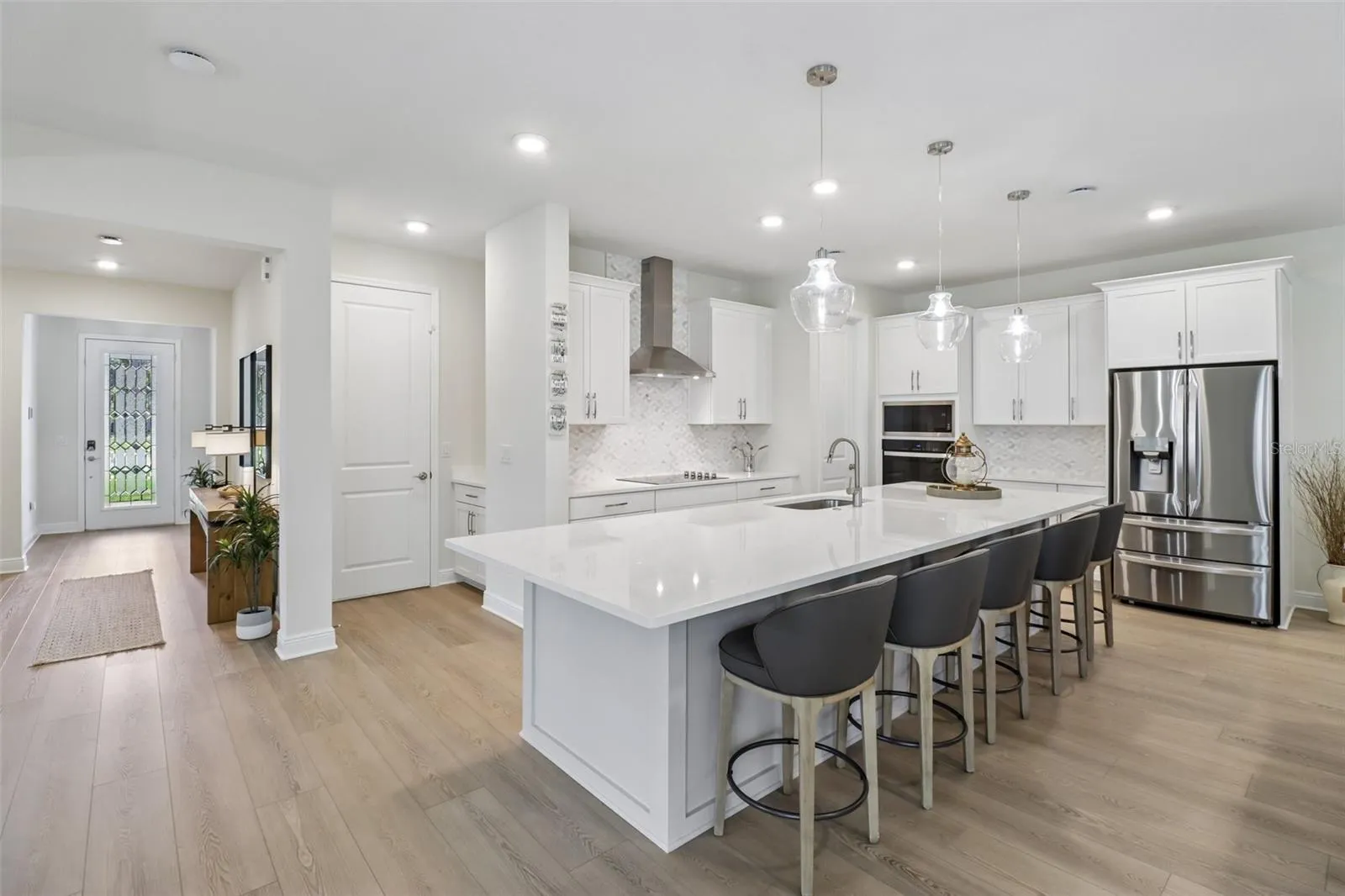 The OPEN-CONCEPT MAIN FLOOR centers around a must-see CHEF'S KITCHEN featuring sleek countertops, extensive cabinetry and storage, a decorative backsplash, pendant lighting, built-in STAINLESS STEEL APPLIANCES and a HUGE ISLAND with bar seating.