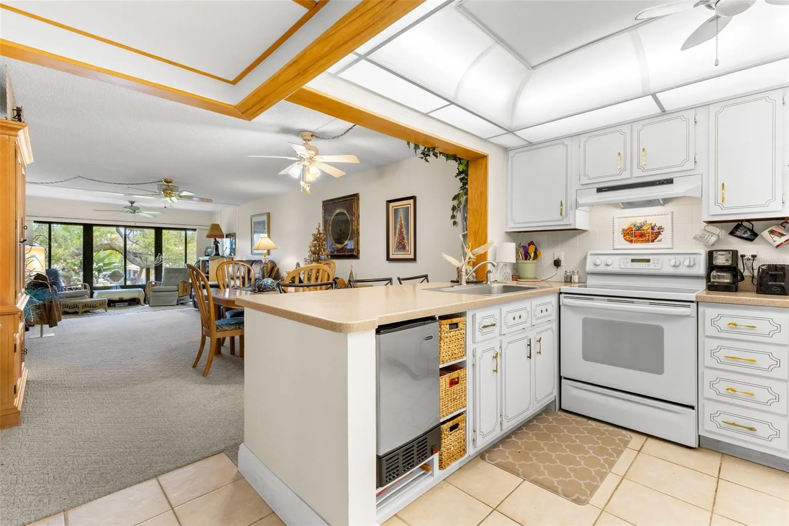 The kitchen opens directly to the dining and living areas, with a generous peninsula providing extra prep space and a clear sightline through the main living area. Ceramic tile, abundant cabinetry and a tray-style ceiling round out the space.