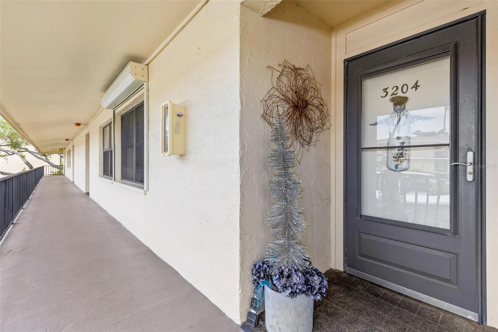 A covered second-floor walkway leads to the unit’s front entry, set along an open-air corridor with railing views across the community.