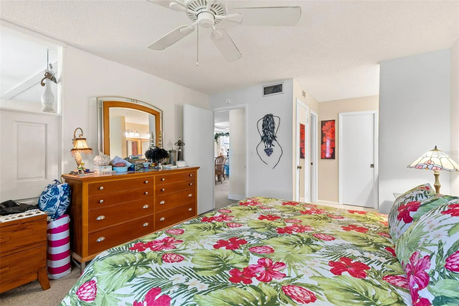 The primary bedroom offers generous space for a full bedroom set, with neutral carpeting, a ceiling fan and direct access to the bath and walk-in closet area.