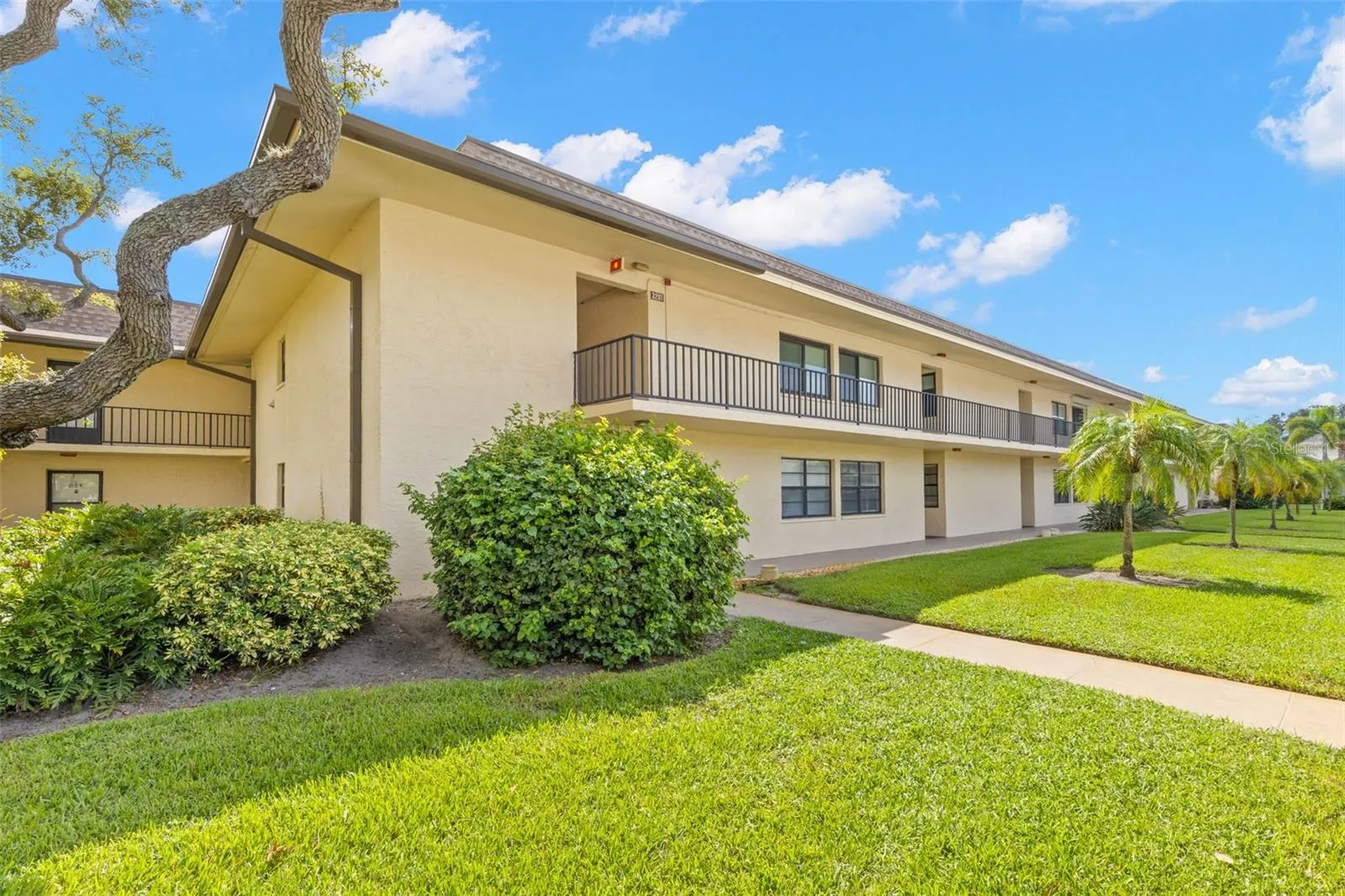 Building 3 is surrounded by open lawn, mature landscaping and palms, with covered walkways along both levels.