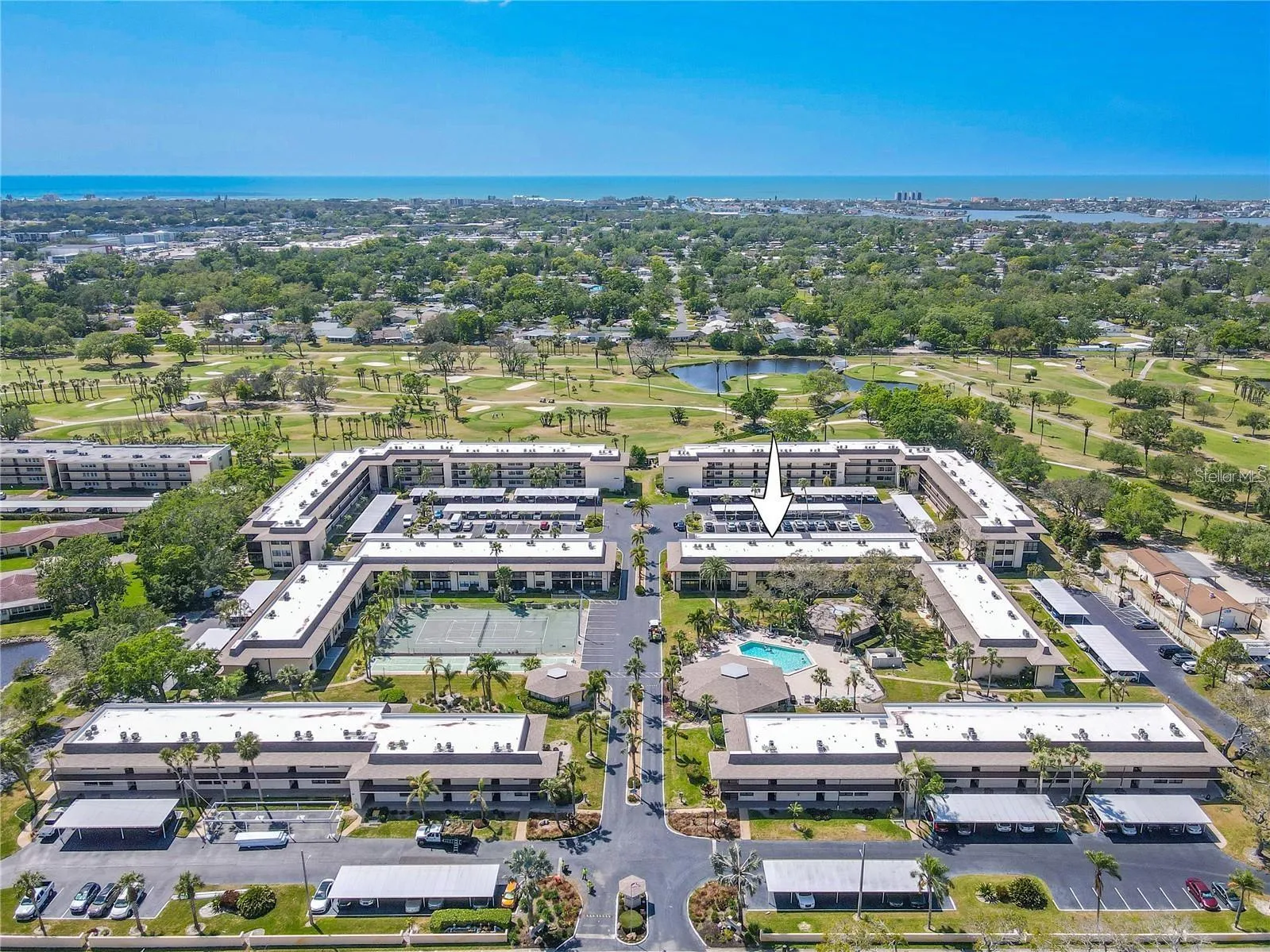 Villas de Golf brings the community amenities into clear focus, with the pool and tennis courts at the center, golf just beyond the property and the Gulf Coast visible in the distance.