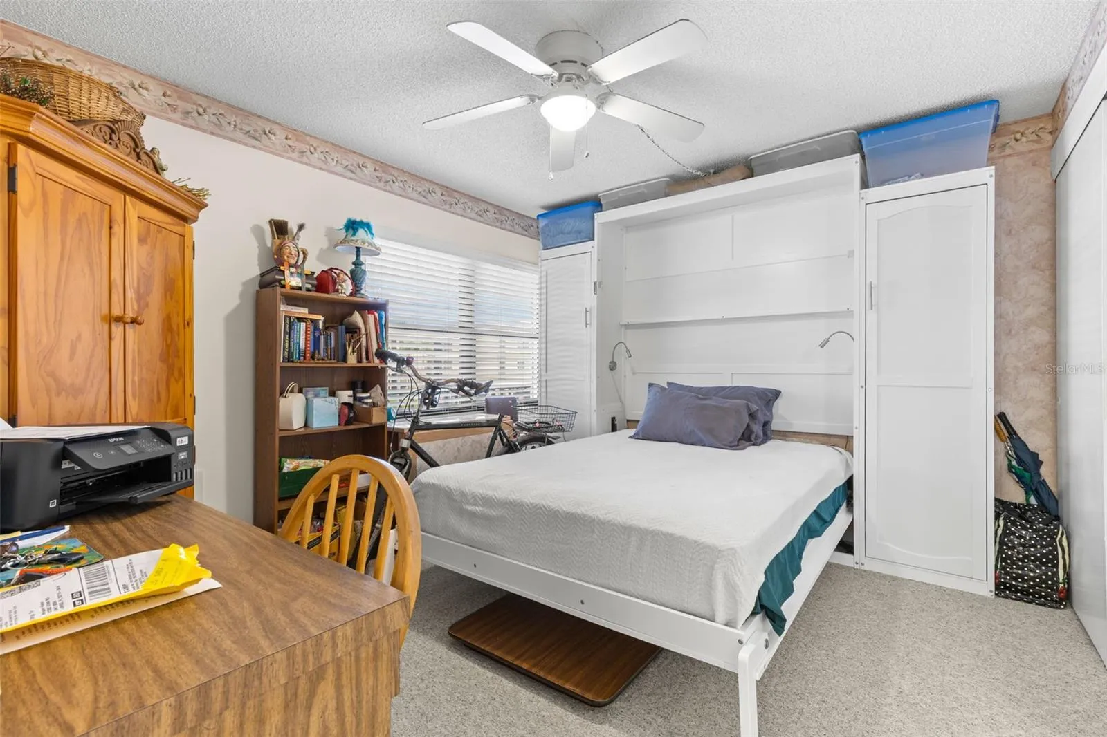 Bedroom 2 measures approximately 11'7" x 10'7", with neutral carpeting, a ceiling fan and a wide window bringing in natural light. The room also has direct access to its own bath, giving it a useful degree of separation from the primary suite.
