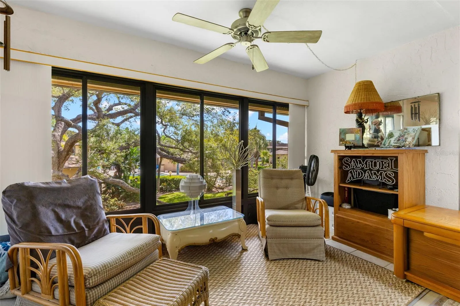 The Florida room has tile flooring, its own ceiling fan and a broad wall of windows overlooking the trees and landscaped grounds. Open to the living room, it adds a separate sitting area without feeling cut off from the rest of the space.