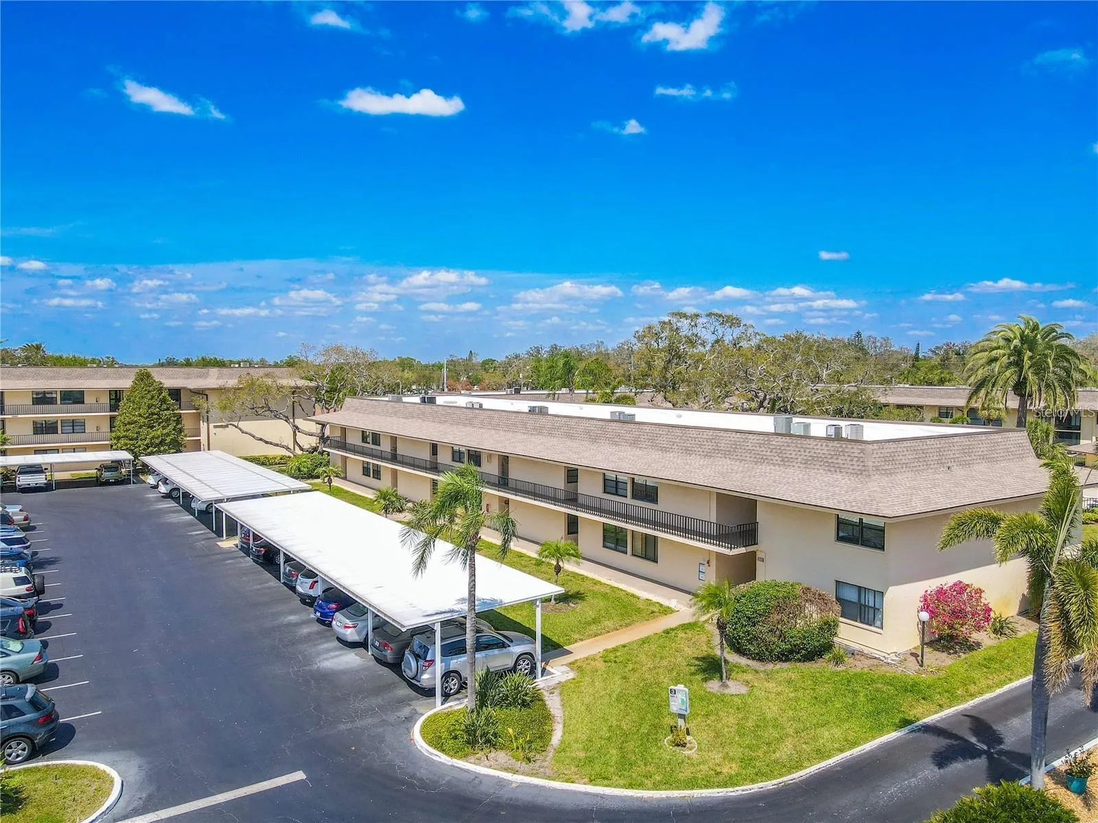 Covered assigned parking runs alongside Building 3, with additional guest parking nearby and landscaped walkways connecting the building to the rest of the community.