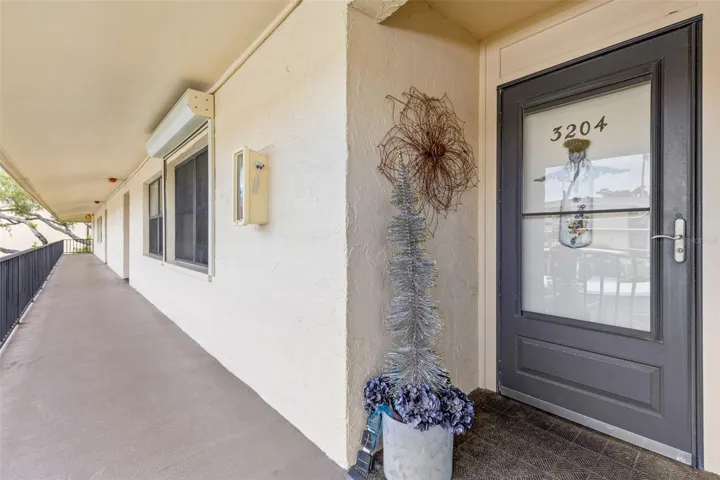 A covered second-floor walkway leads to the unit’s front entry, set along an open-air corridor with railing views across the community.