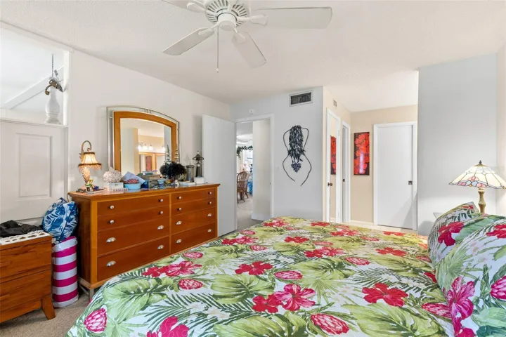 The primary bedroom offers generous space for a full bedroom set, with neutral carpeting, a ceiling fan and direct access to the bath and walk-in closet area.