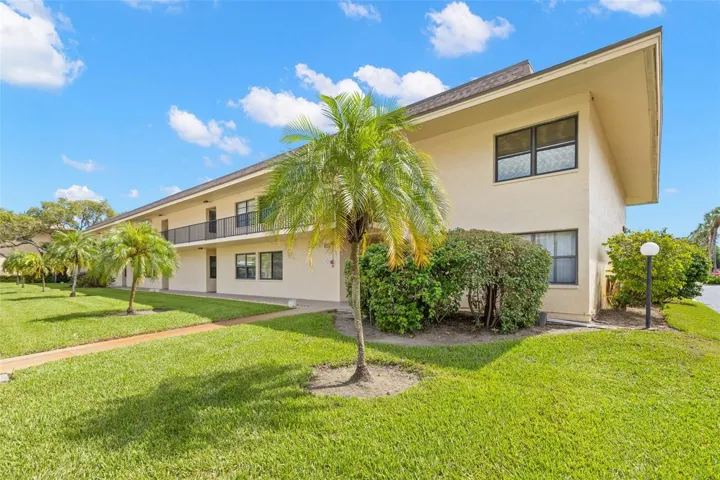 Mature palms, open lawn and landscaped grounds surround Building 3, with a paved walkway leading to the second-floor residences.