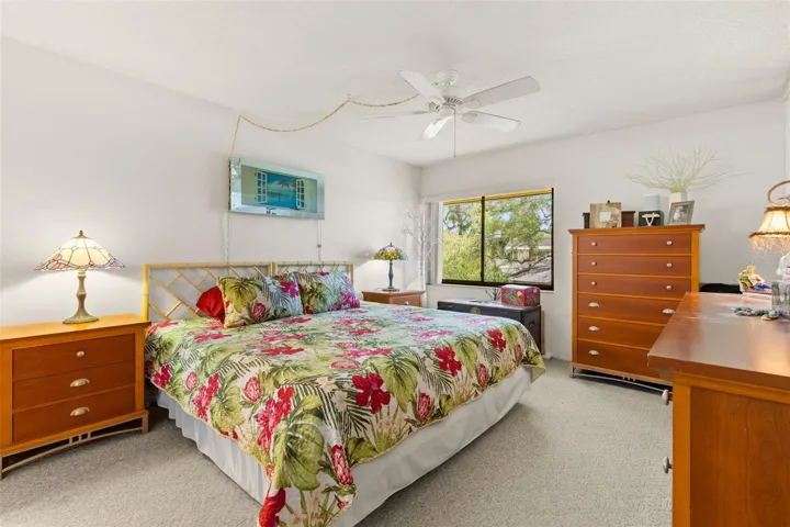 The primary bedroom measures approximately 11'10" x 13'7", with neutral carpeting, a ceiling fan and a wide window overlooking the trees. The room has enough wall space for a full bedroom set without feeling crowded.