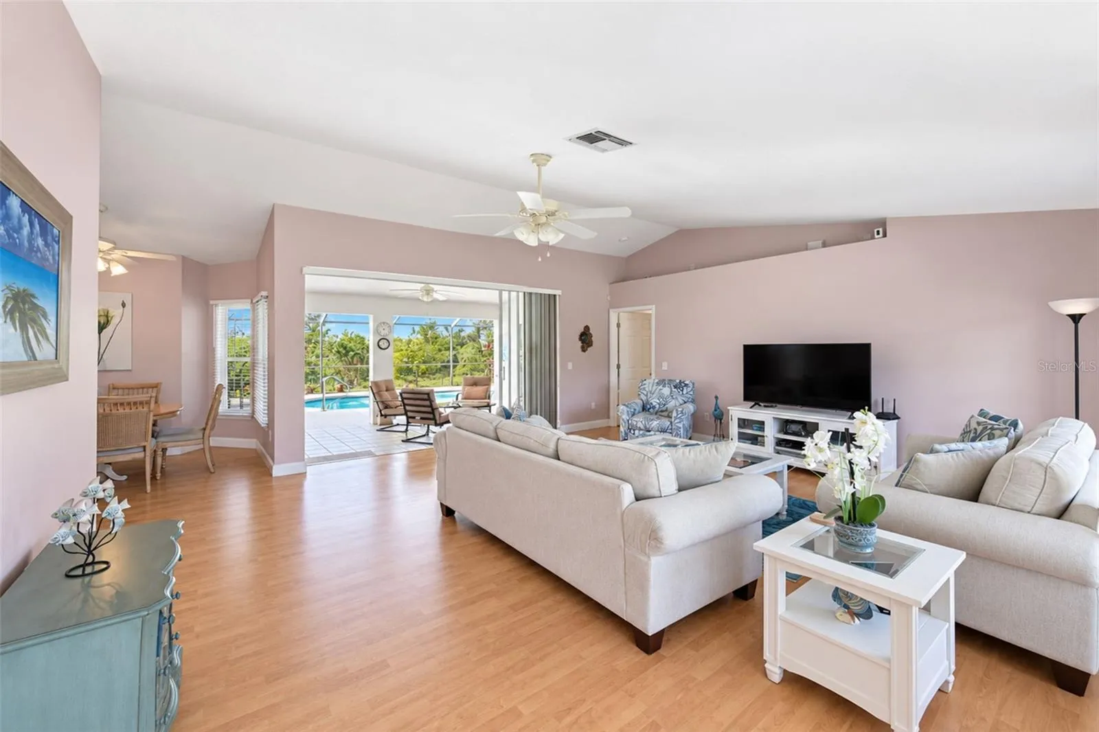 The living room has a ceiling fan, laminate flooring and sliding glass doors to the lanai.