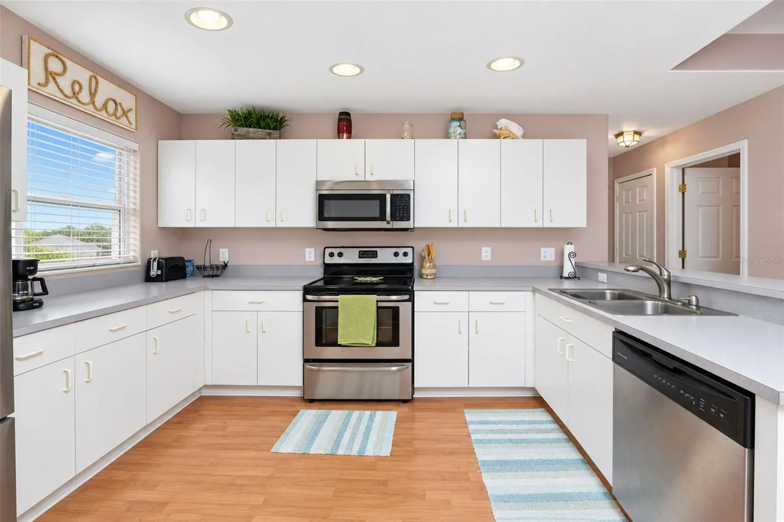 The kitchen has laminate flooring, a window for natural light and plenty of cabinetry for storage.