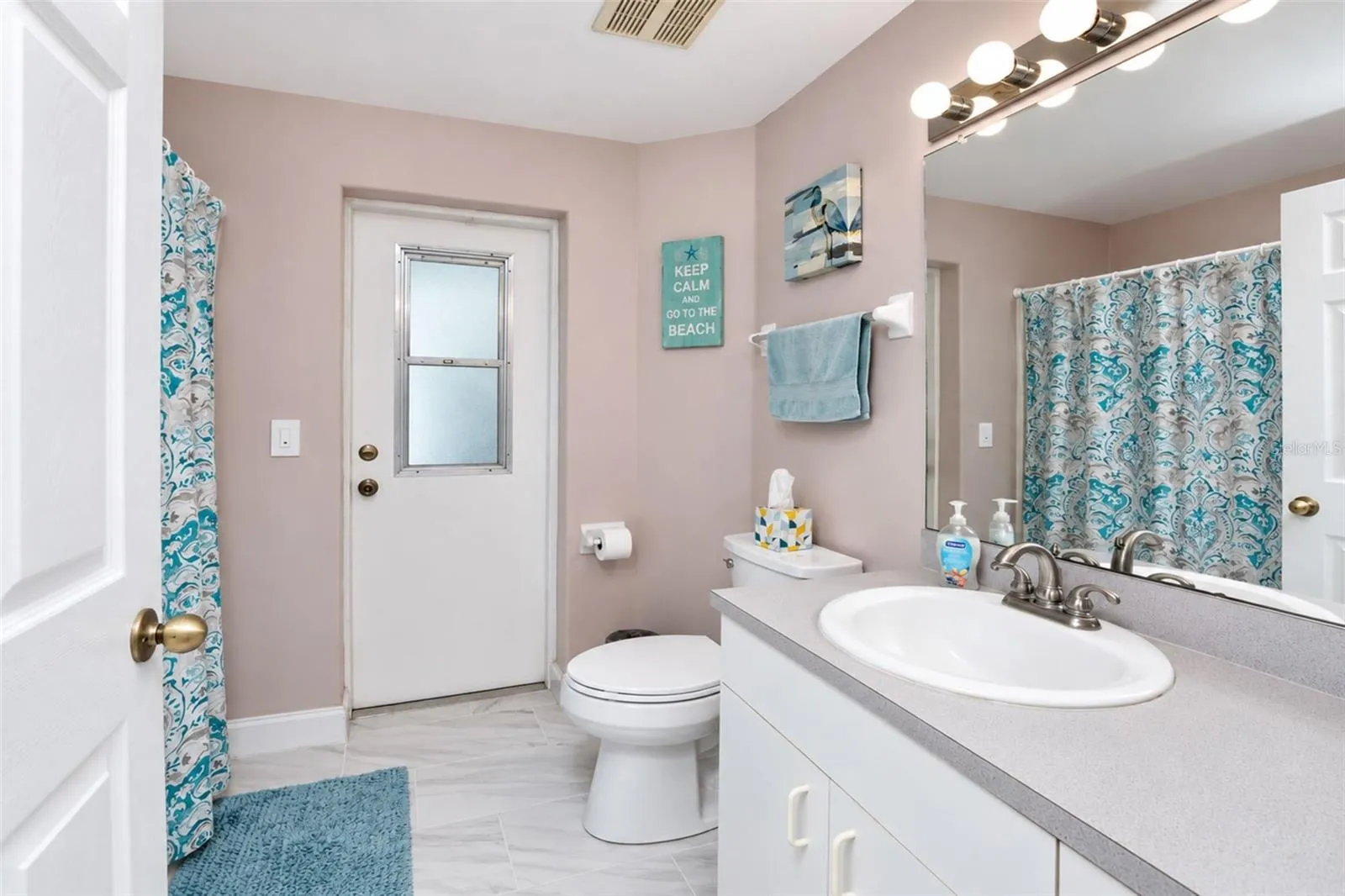 The guest bathroom has tiled flooring, good sized vanity and direct access to the lanai & pool.