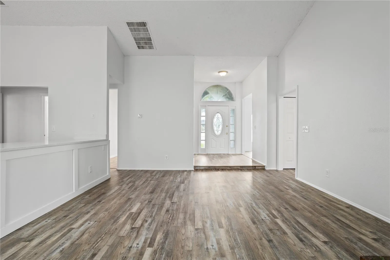 From the family room, you see the kitchen, front door, and doorways leading to dining and living rooms.