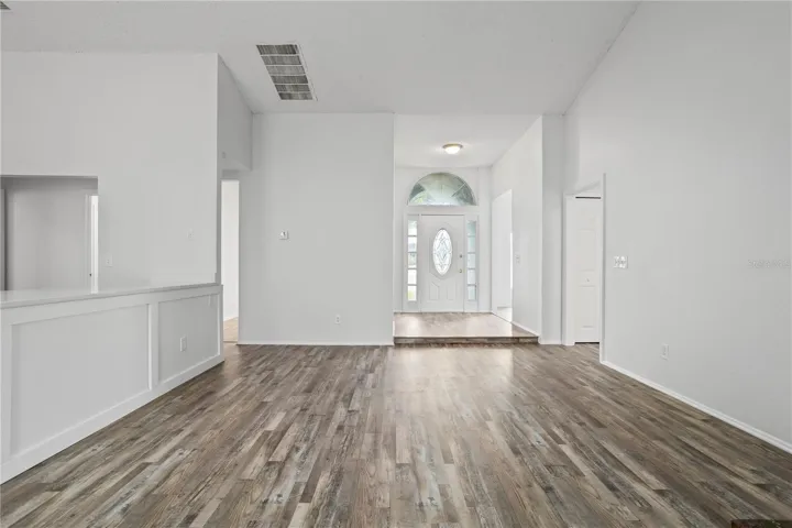 From the family room, you see the kitchen, front door, and doorways leading to dining and living rooms.