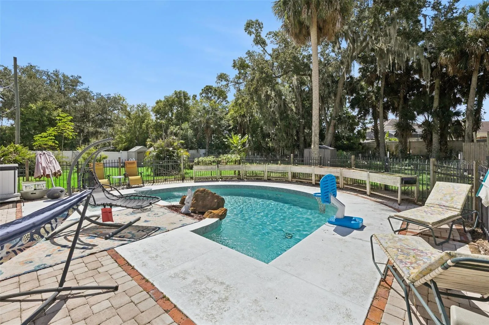 The saltwater pool is surrounded by mature trees and opens naturally to the property's unusually generous backyard.