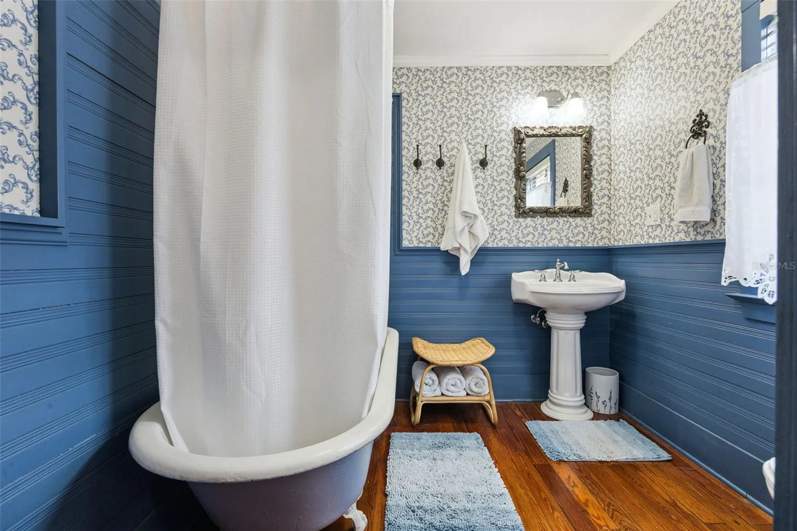 Vintage character continues in the bath with a clawfoot tub, pedestal sink, beadboard detailing and wood floors.