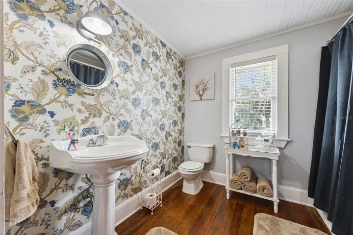 A second beautifully styled bath pairs a clawfoot tub and pedestal sink with classic black-and-white tilework.