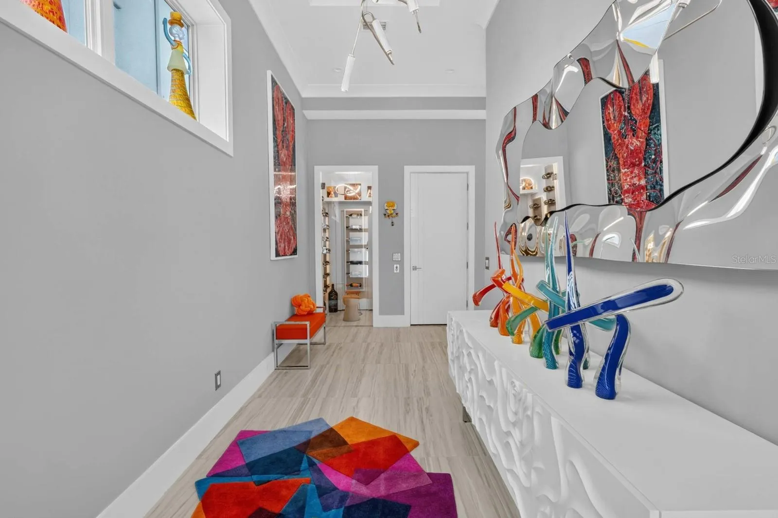 A gallery-like arrival. Soaring ceilings, statement lighting and custom finishes lead you toward one of the home’s unexpected details...the dedicated wine room.