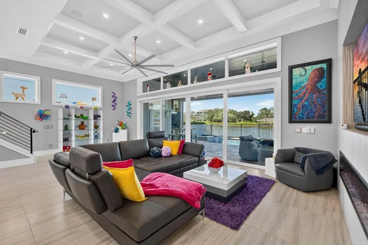 Main-level gathering space with a sleek electric fireplace, integrated entertainment wall and direct connection to the covered outdoor living, pool and Intracoastal.
