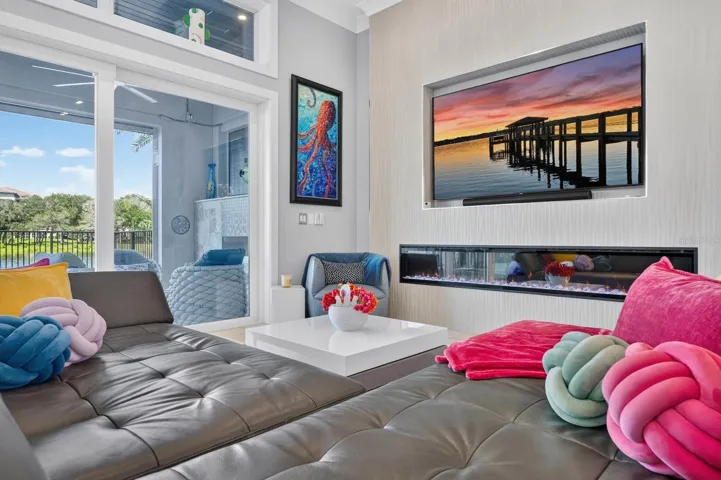 A dramatic linear fireplace anchors the living room, while walls of glass create an effortless connection to the covered lanai, pool and water beyond.
