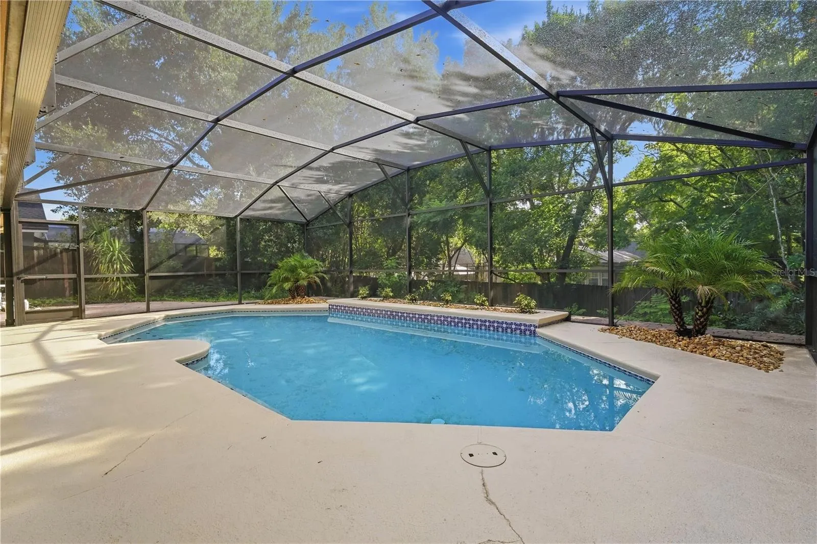 Private screened pool surrounded by mature landscaping.