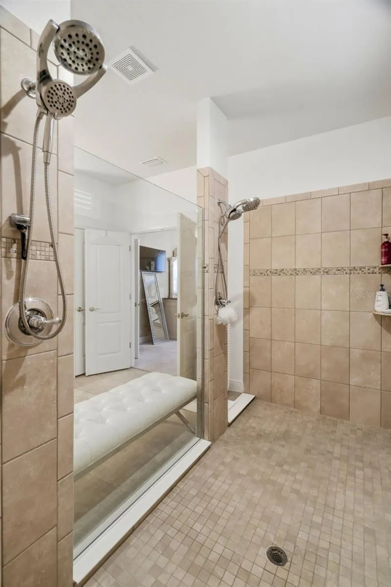 Oversized tiled walk-in shower with built-in bench and multiple shower niches.