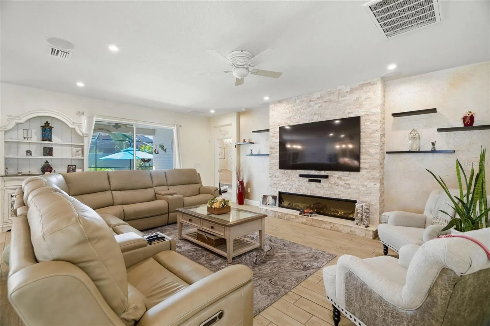 Custom stacked-stone entertainment wall with floating shelving creates a dramatic focal point in the living room.