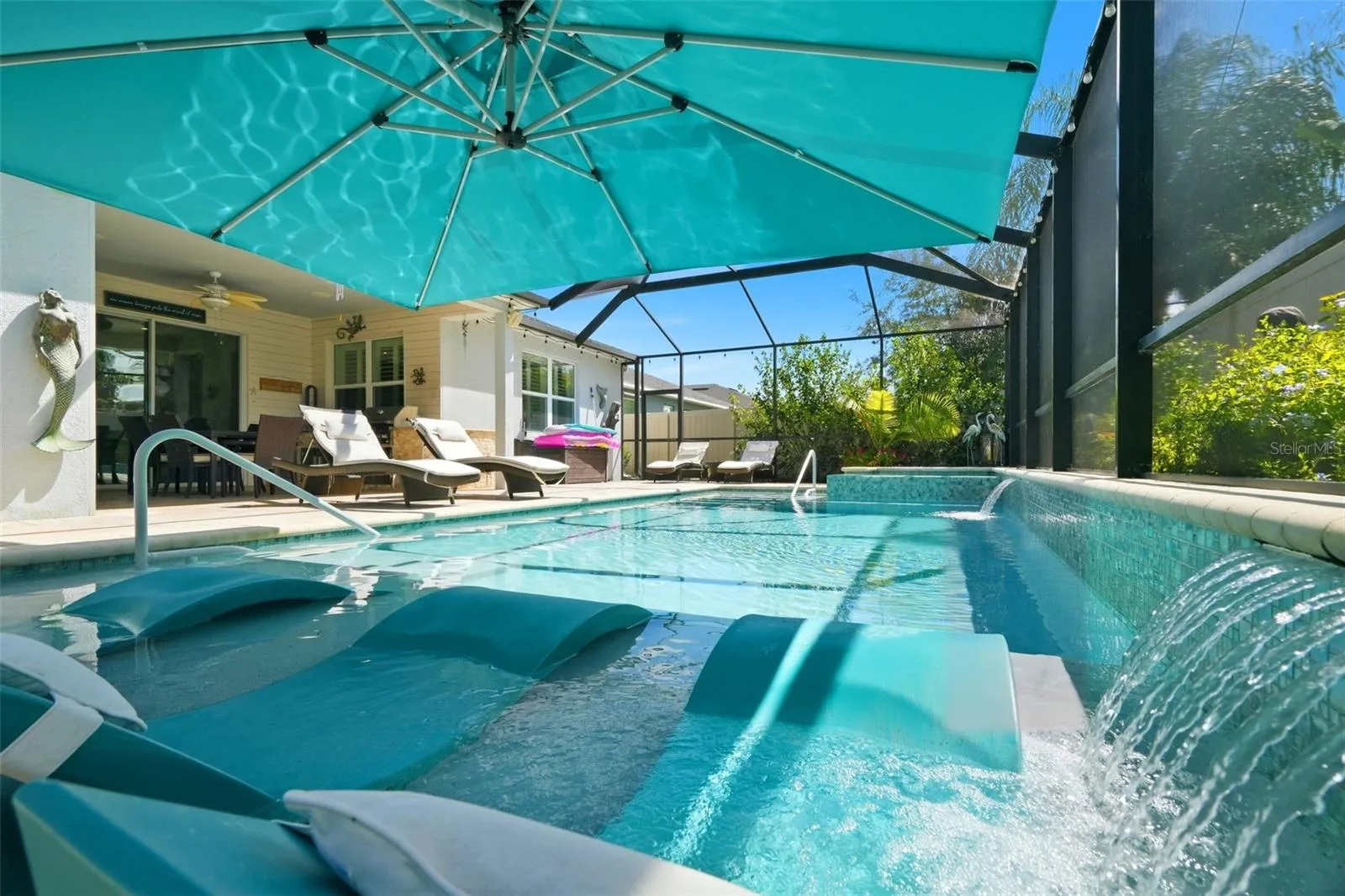Screened saltwater pool with sun shelf, oversized 10' x 12' umbrella and multiple water features.
