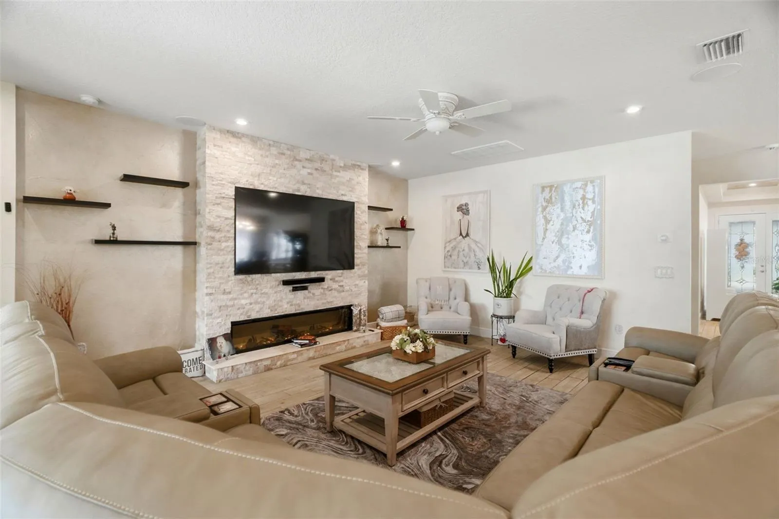 Spacious living area with recessed lighting, custom wall finishes and direct flow into the kitchen.Bright, open living room with large-format tile flooring and custom interior finishes.
