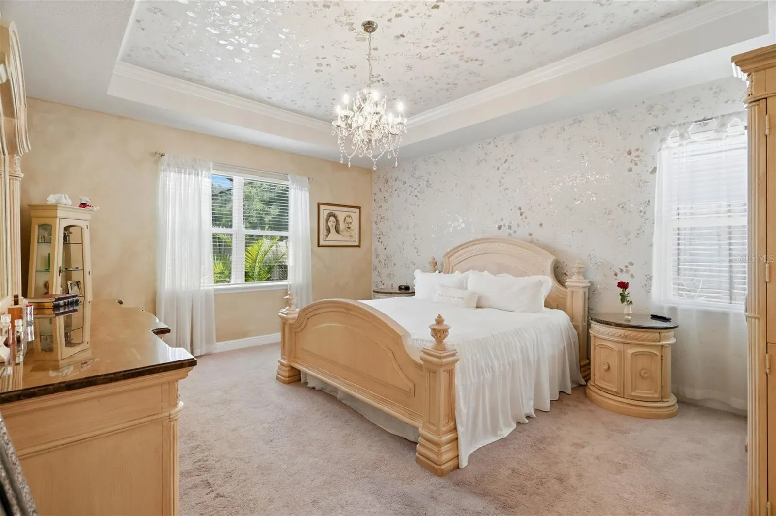 Spacious primary suite with tray ceiling and custom decorative wall and ceiling finishes.