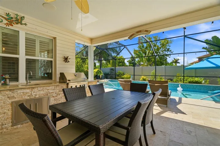Covered lanai and custom outdoor kitchen create an ideal indoor-outdoor entertaining space. All outdoor furniture conveys.