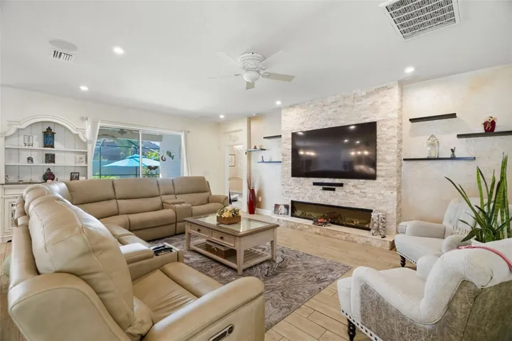 Custom stacked-stone entertainment wall with floating shelving creates a dramatic focal point in the living room.