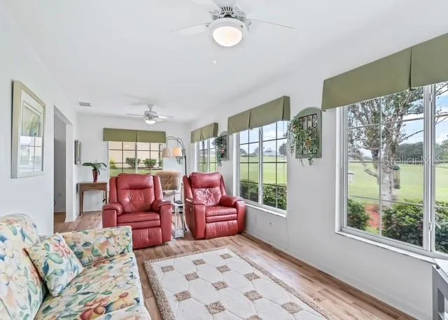 Bright and inviting living space features an abundance of windows that fill the room with natural light while showcasing beautiful golf course views.