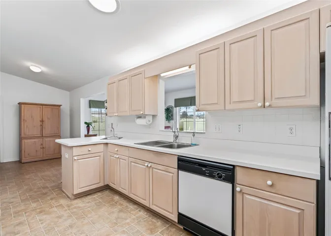 Large, bright kitchen featuring abundant cabinetry and generous counter space. A double sink and additional smaller sink provide added convenience and functionality, making this kitchen well-suited for everyday living and entertaining.