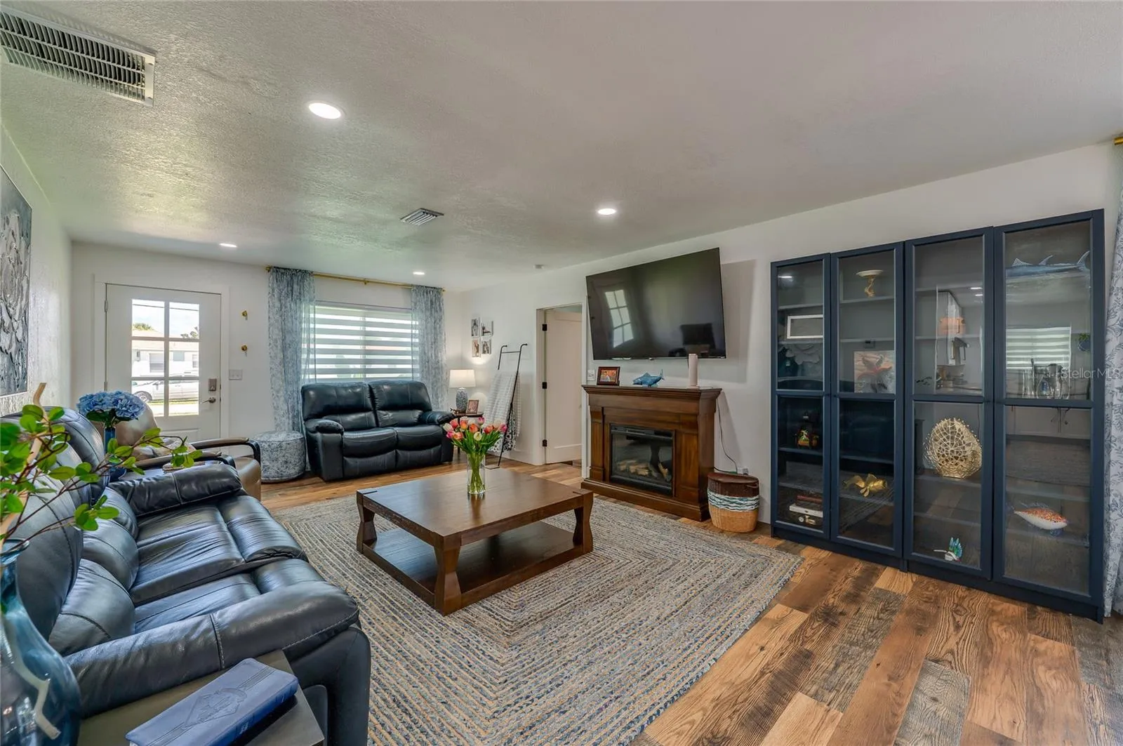 Generously sized main living space featuring rich LVP flooring under soft recessed lighting.
