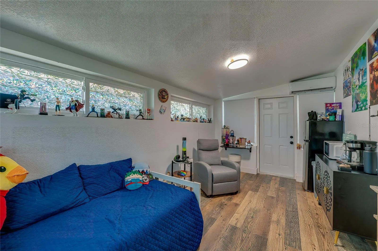 Versatile bedroom or multipurpose living space highlighting rich LVP flooring, sloped ceilings, and long horizontal windows that offer plenty of natural light.
