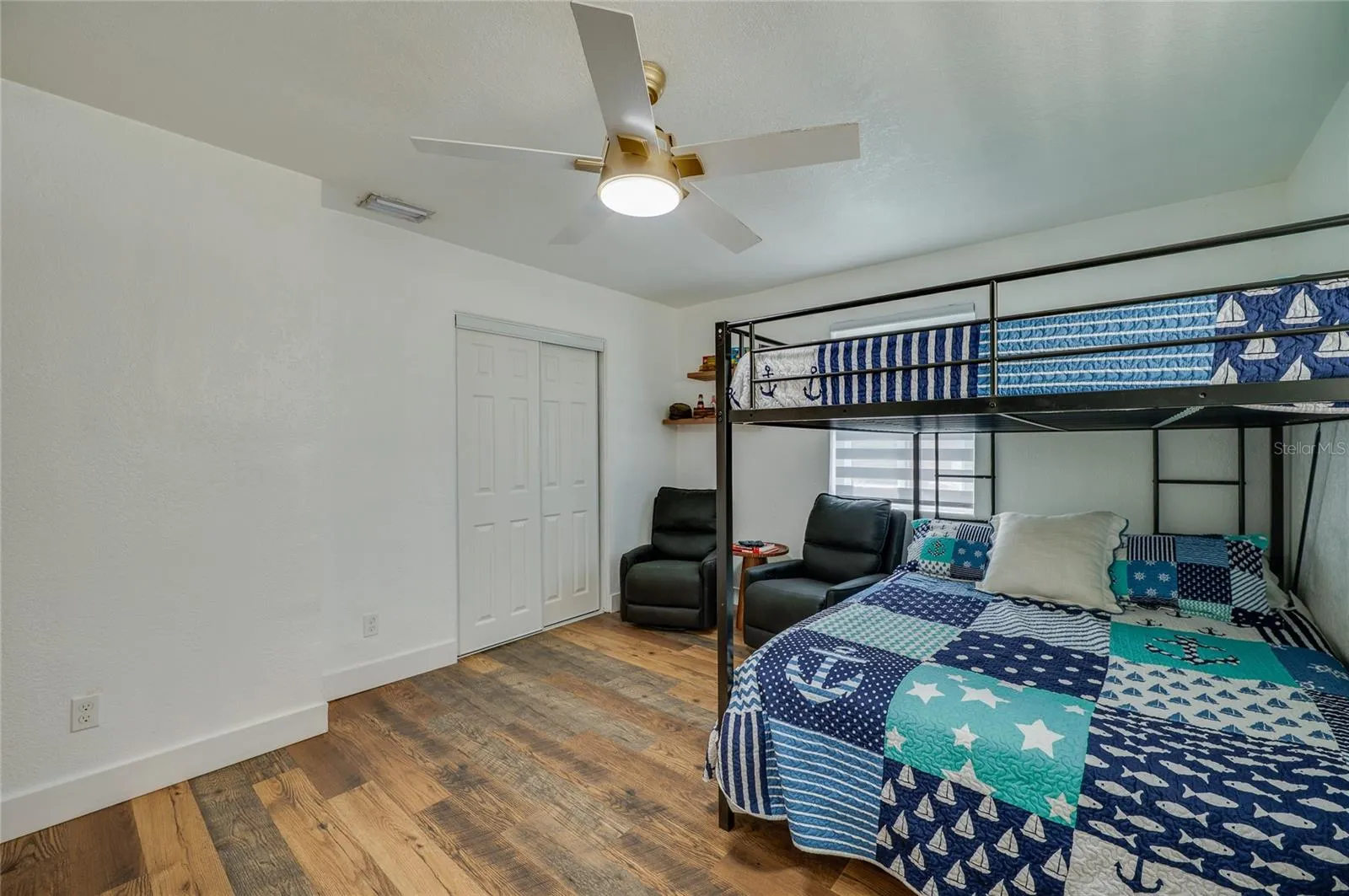 Bedroom view showcasing bright neutral walls, a ceiling fan, double sliding closet doors, and LVP flooring throughout.