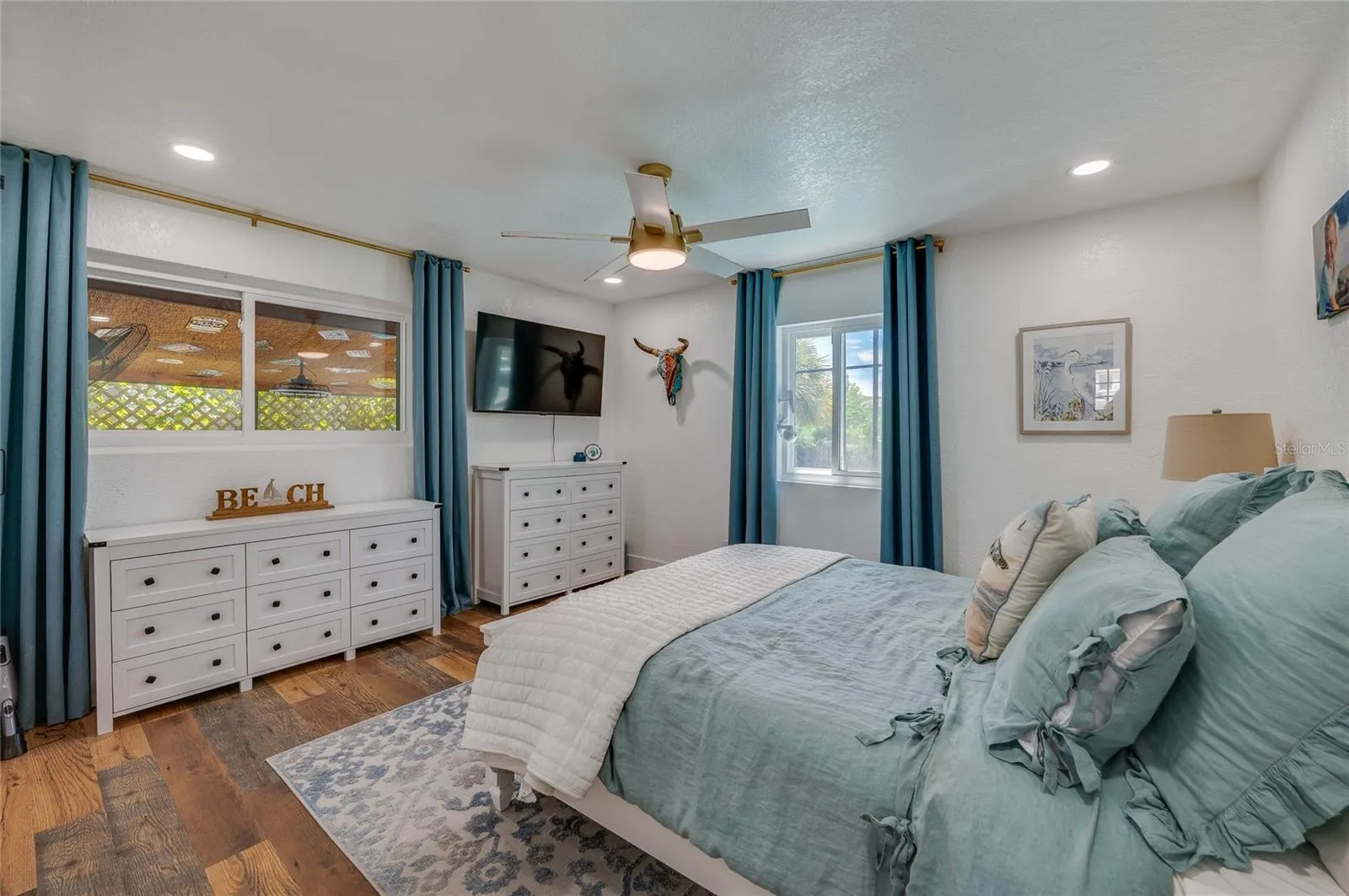 Light-filled bedroom featuring double windows, LVP flooring, and recessed ceiling lighting with a matching ceiling fan.