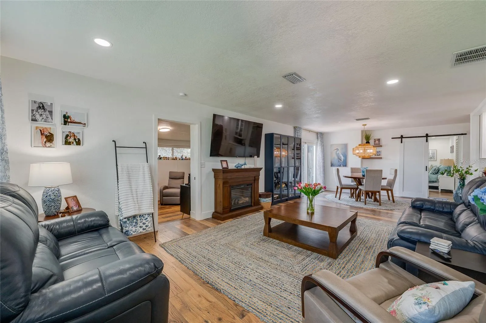 Spacious open-concept living area with warm LVP flooring, recessed lighting.