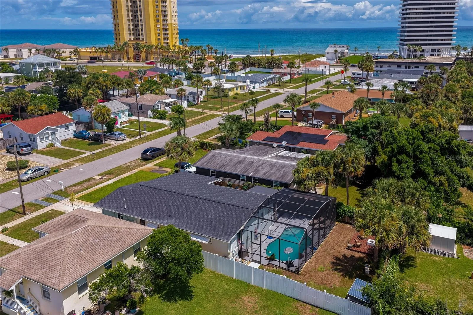 High-angle aerial photo displaying the home’s layout, complete with its screened-in pool area, private yard, and proximity to the coastline.