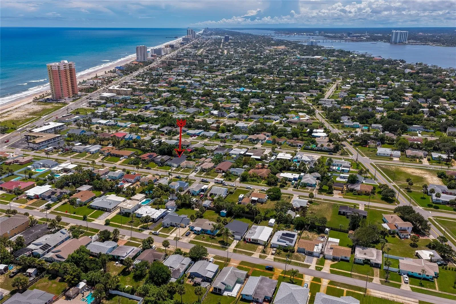 High-altitude aerial view highlighting the property within the vibrant coastal community, positioned just blocks away from the ocean and riverfront.