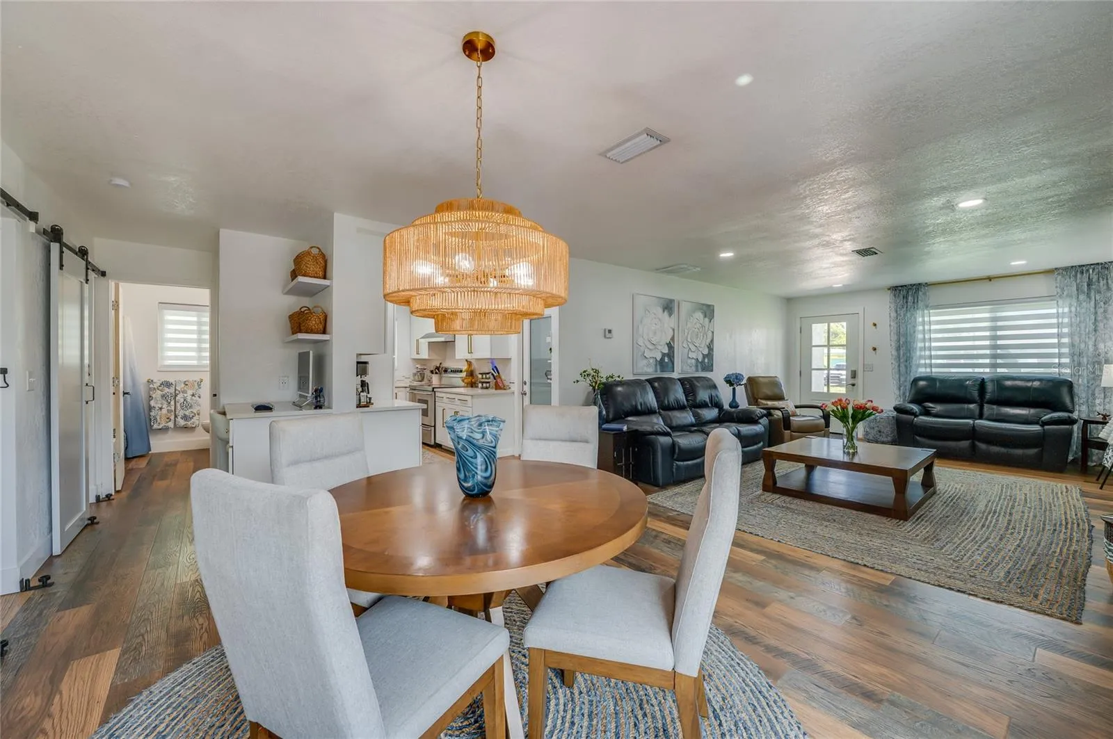 Expansive view of the open-plan main level showing the fluid transition from the dining space through to the main living area and kitchen entry.