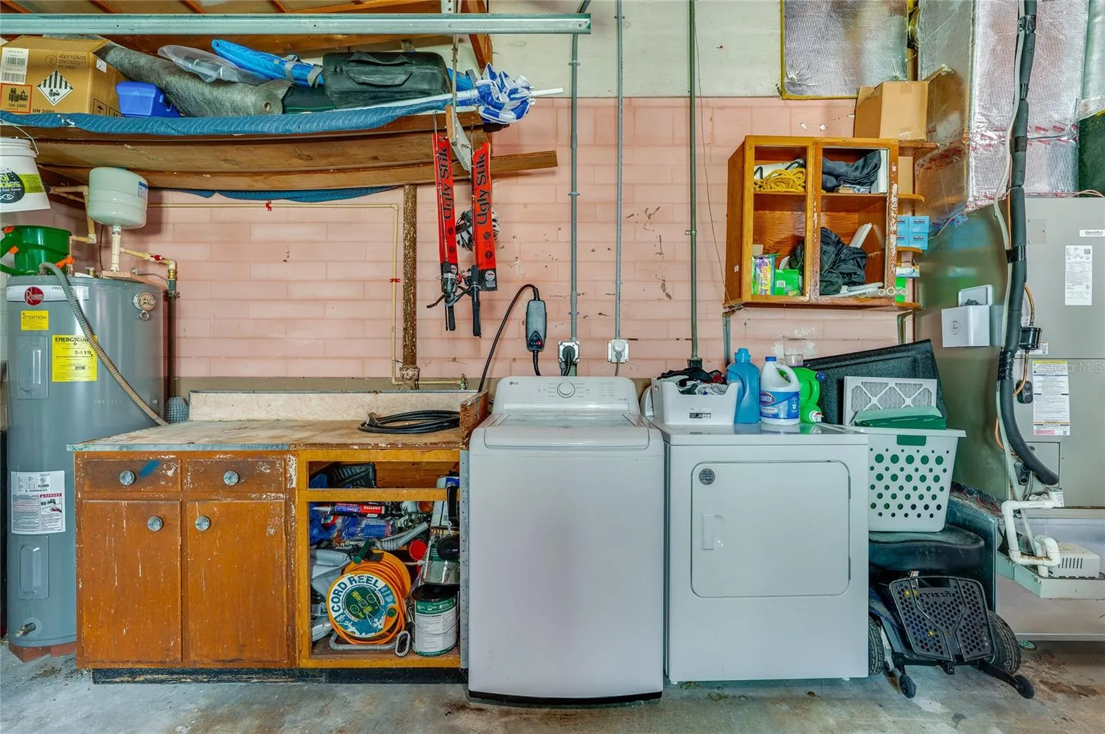 Dedicated utility station in the garage offering a washer and dryer alongside a built-in workbench and open storage shelves.