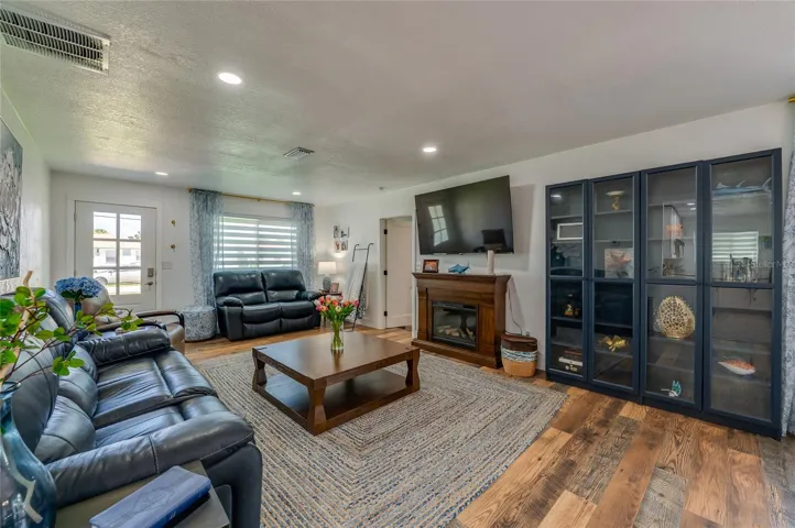 Generously sized main living space featuring rich LVP flooring under soft recessed lighting.