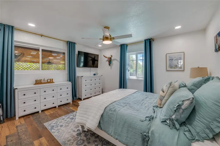 Light-filled bedroom featuring double windows, LVP flooring, and recessed ceiling lighting with a matching ceiling fan.
