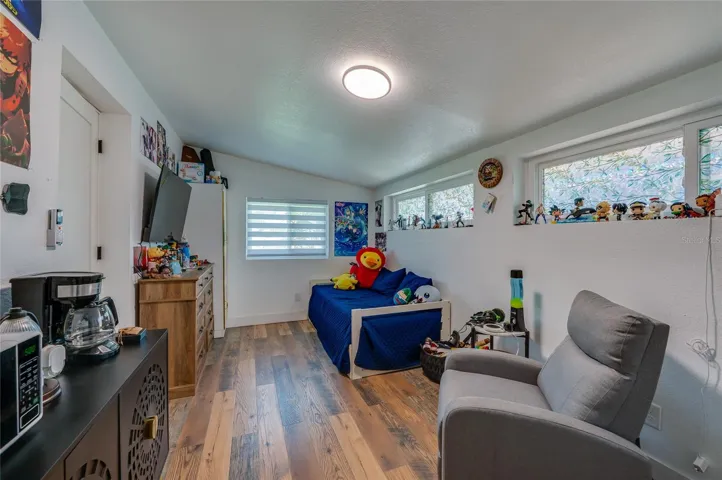 Cozy bedroom featuring LVP flooring, sloped ceilings, ample natural light from multiple windows, and smooth neutral walls.